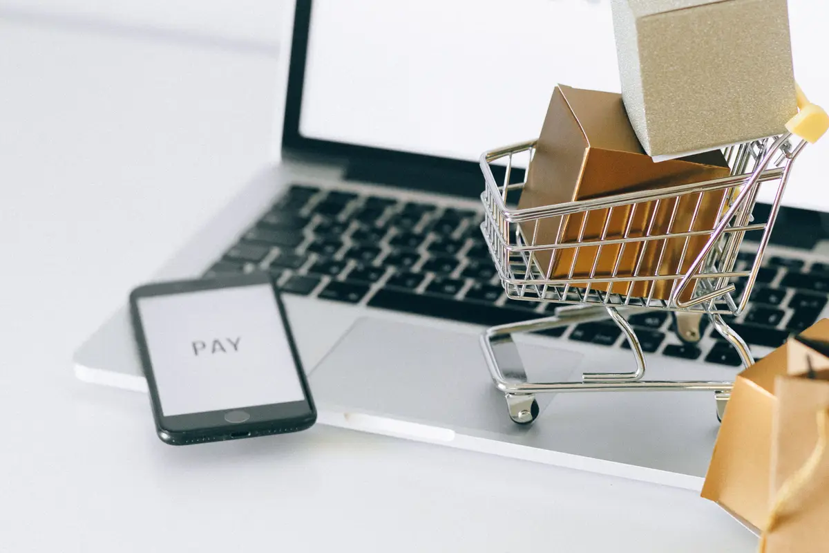 Notebook com um carrinho de compras em miniatura cheio de caixas