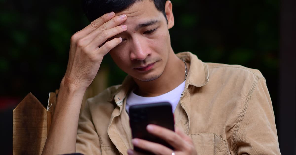 Homem cansado olhando o celular à noite