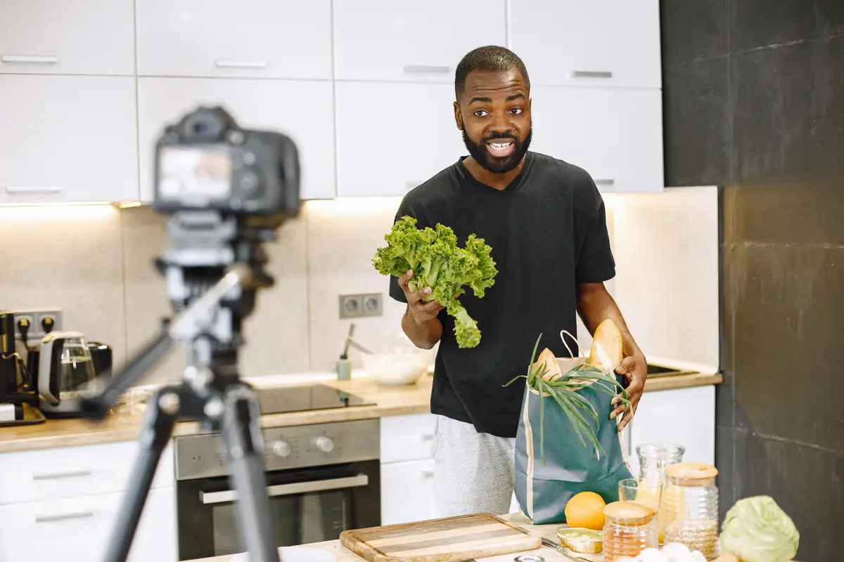 Homem na cozinha gravando com a câmera no tripé
