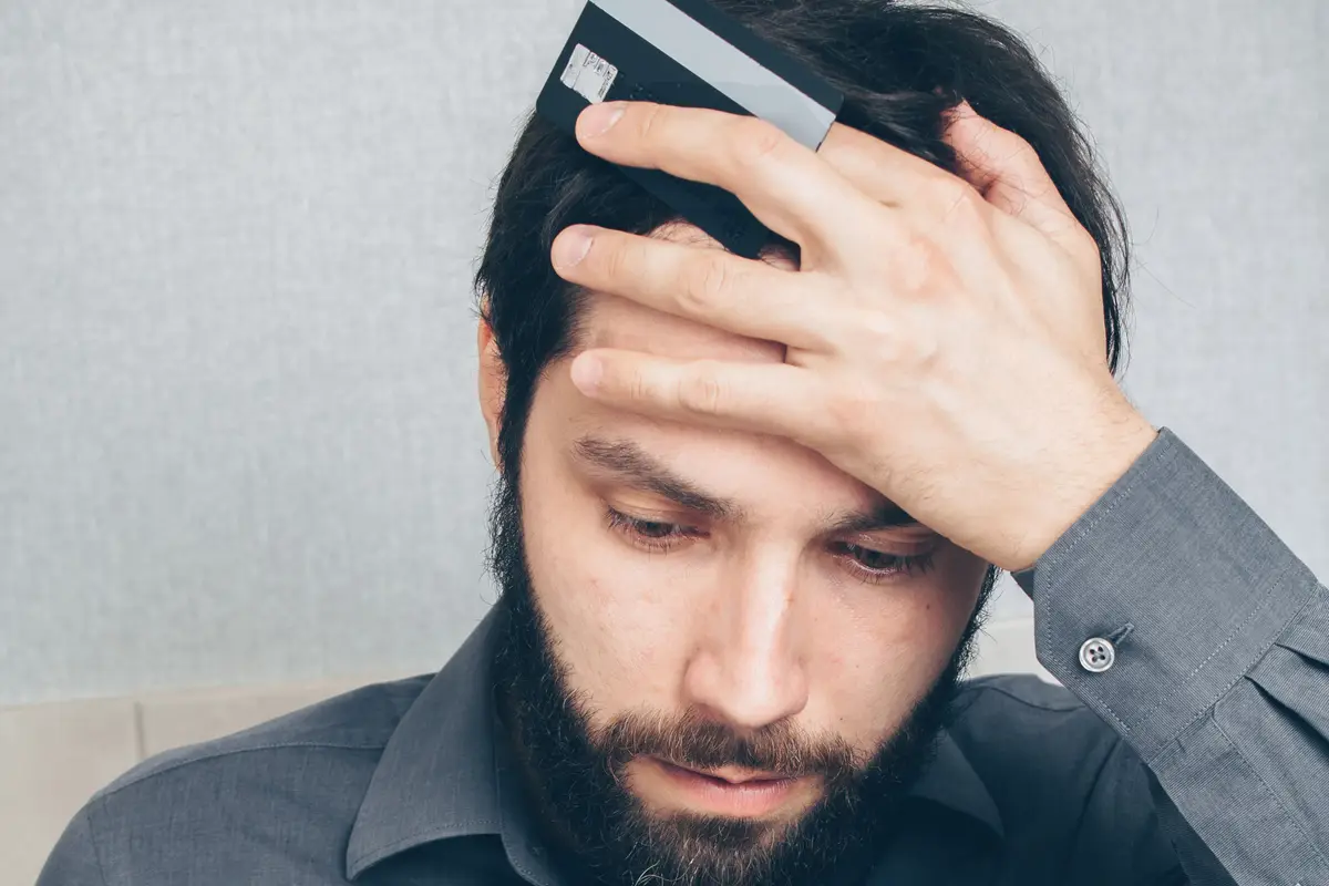 Homem frustrado com o celular e o cartão na mão