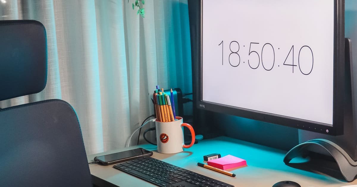 Monitor mostrando o relógio numa mesa escura