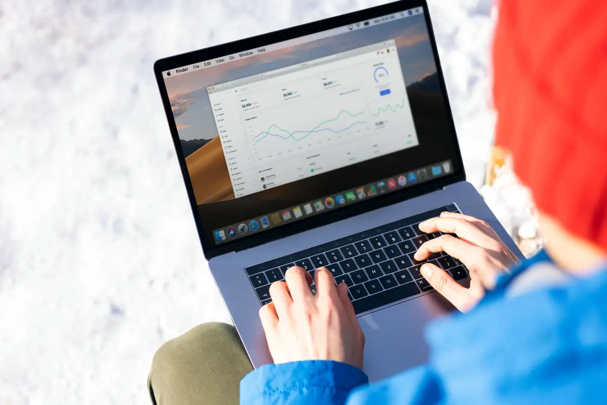 Mãos digitando num notebook com um painel de métricas na tela