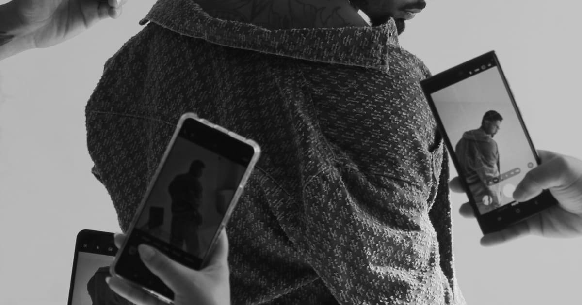 Homem cercado por celulares apontados para ele, em preto e branco