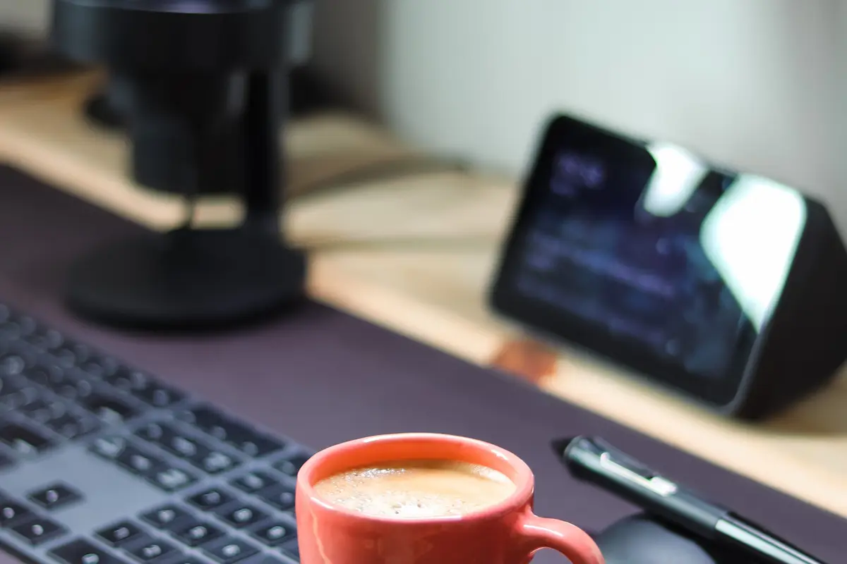 Mesa com microfone, café e monitor
