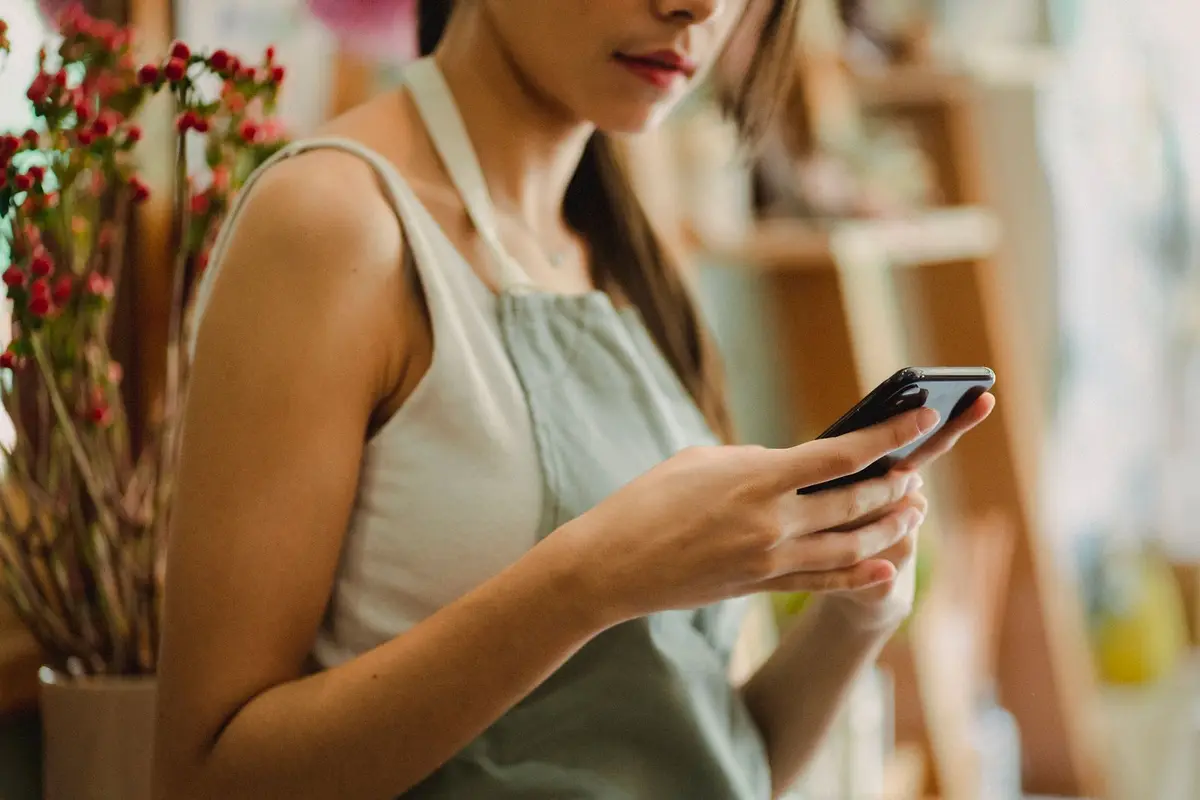 Dona de floricultura conferindo o celular na loja