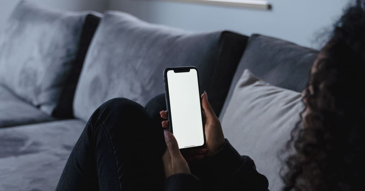 Pessoa no sofá lendo uma mensagem no celular