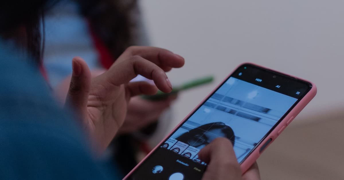 Mão segurando um celular com um aplicativo de mensagens aberto