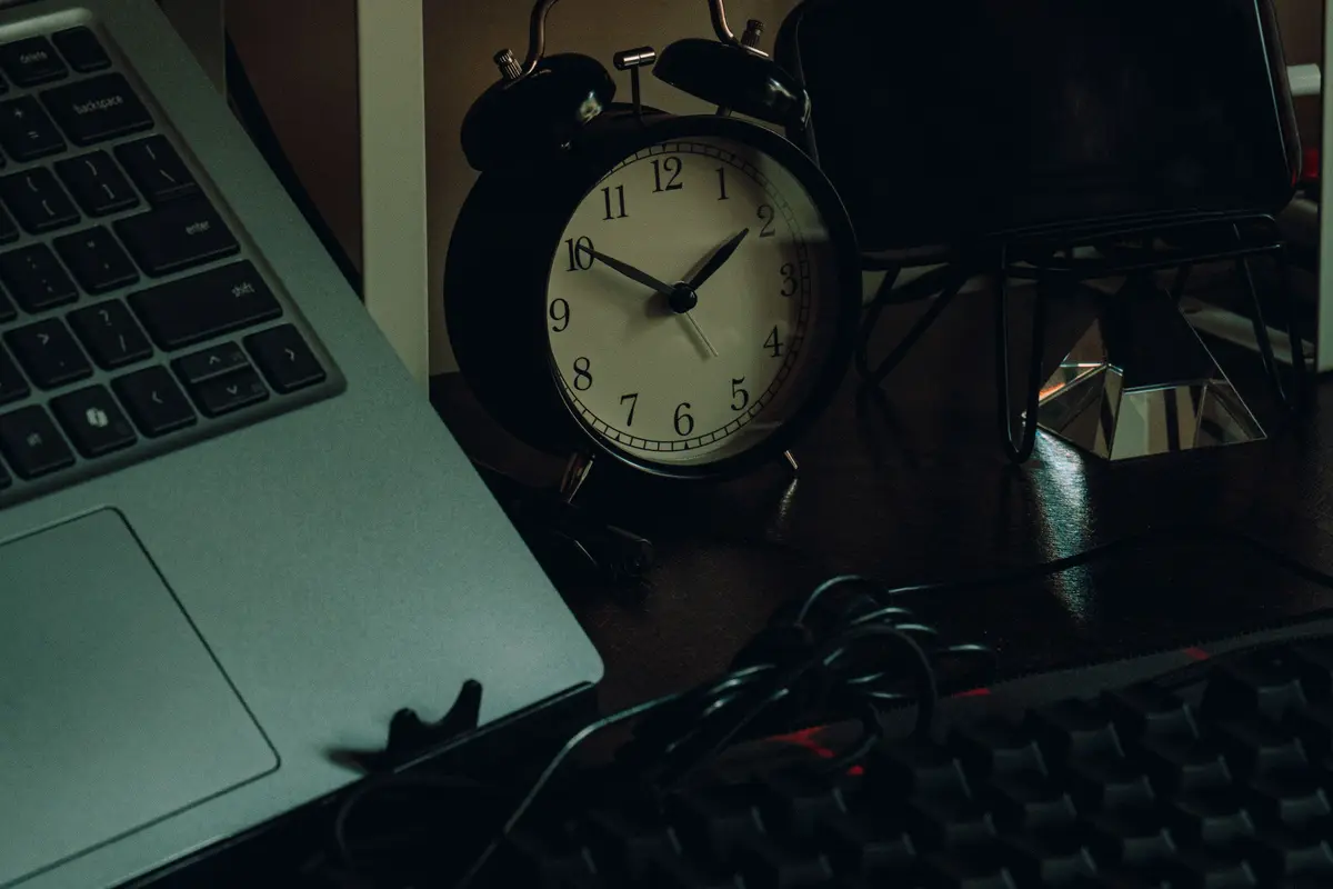 Notebook e relógio numa mesa escura