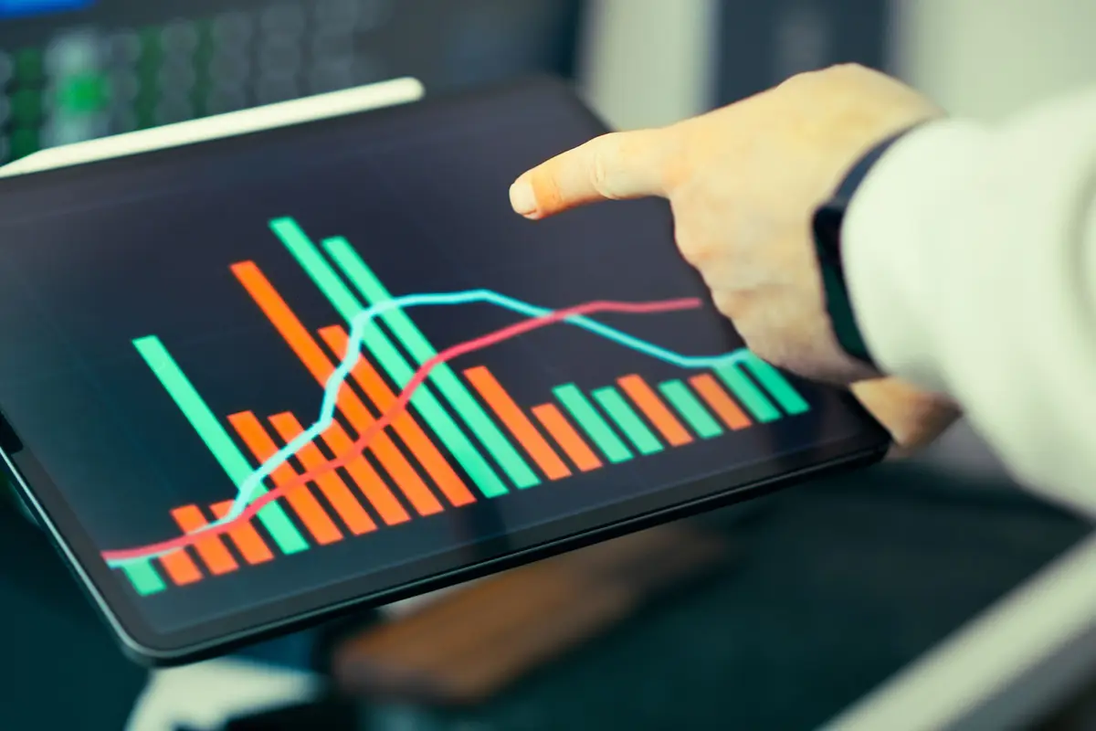 Pessoa apontando para um gráfico de barras num tablet